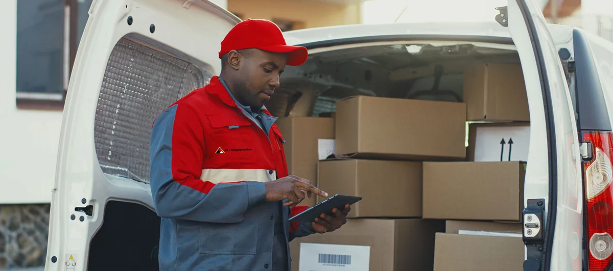Delivery driver in a red EX Transportation uniform loading boxes into a van